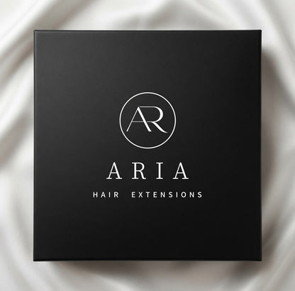 Schwarze ARIA HAIR Verpackung für Extensions auf hellem Stoff